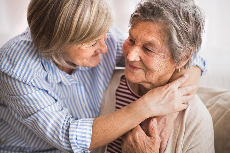Daughter hugging her mother concept image for signs of Alzheimer's disease.