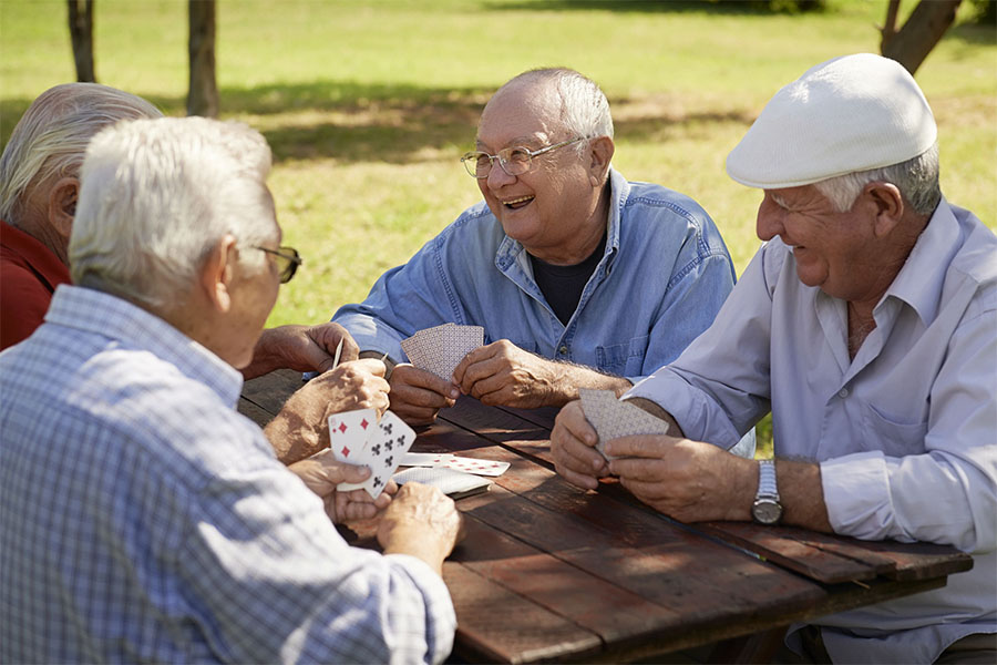Group of seniors playing cards at the park and having fun concept image for how does socialization help older adults